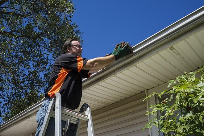 worker fixing a broken gutter on a house in Easton, KS