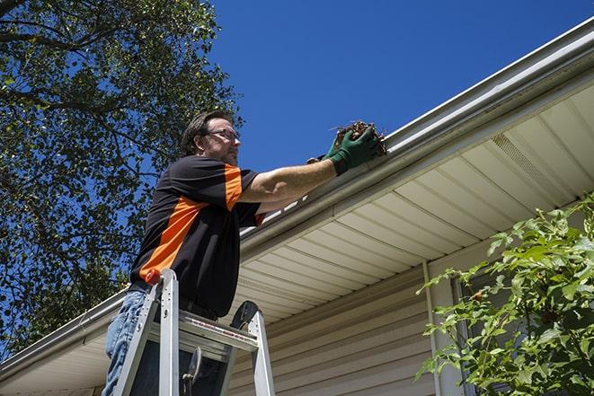 a person repairing a gutter on a residential roof in Osawatomie KS